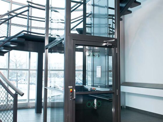 灰色框架Savaria V-1504电梯，采用透明外壳嵌件，位于现代2层门厅中